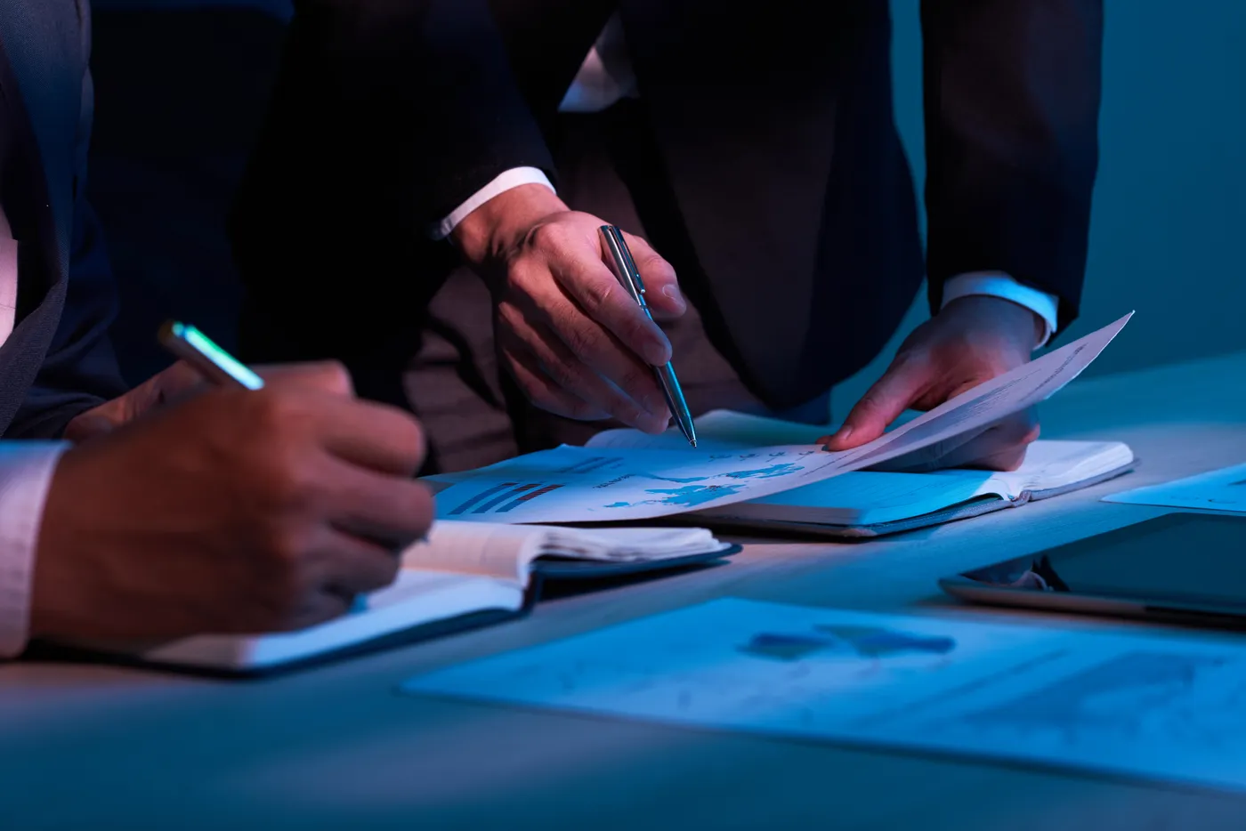 Auditor taking notes while reviewing supplier records during an audit meeting